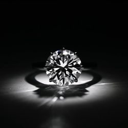 Bir tane elmas yüzük siyah beyaz ve loş bir ortamda bakılırken yüzüğün üstüne beyaz bi ışık yansicak estetik fotoğraf